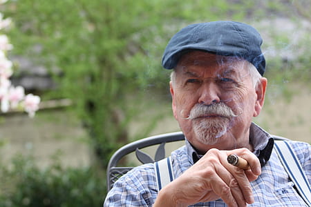 man holding cigar sitting on gray chair thumbnail