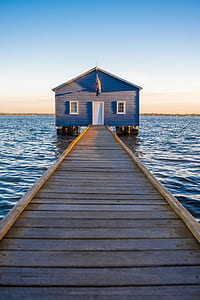 brown wooden beach dock leading into blue and grey wooden shedf thumbnail