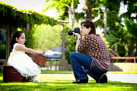 woman taking photo of girl holding box thumbnail