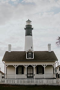 lighthouse behind wooden house thumbnail