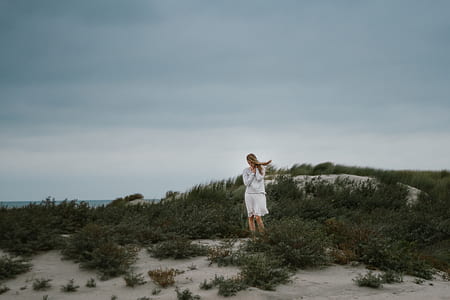 woman standing on sand near ocean thumbnail