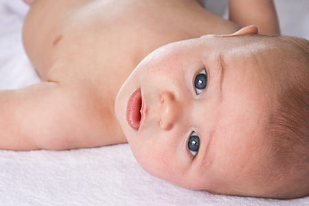 baby lying on white textile portrait photo thumbnail