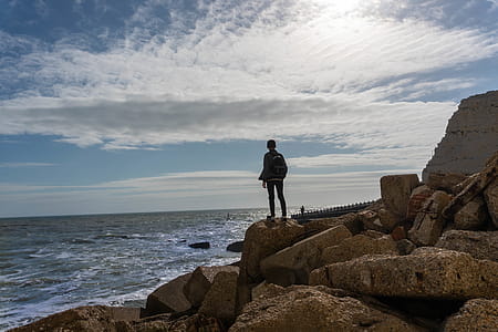 Person Standing on Rock in Front of Sea thumbnail