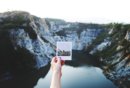 person holding photo of woman standing on hill thumbnail