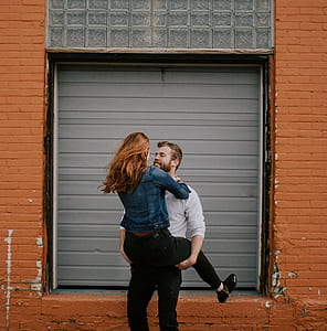 man carrying woman near gray metal roller shutter thumbnail