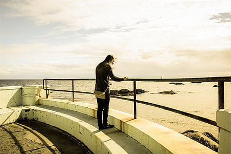 person standing on railing near water thumbnail