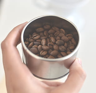 person holding gray container with coffee beans thumbnail