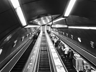 low-angle photography of people on escalator greyscale photography thumbnail