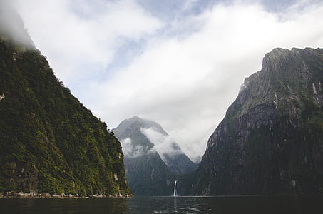 calm river near waterfalls and mountains with fogs at daytime thumbnail