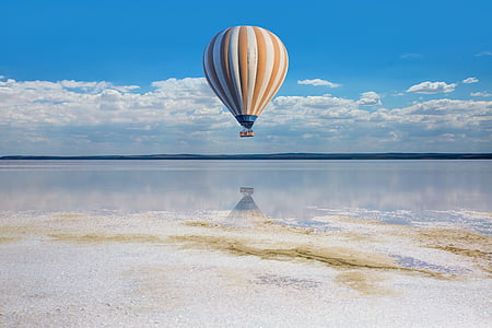 yellow and white hot air balloon above clear water under white clouds and blue sky during daytime thumbnail