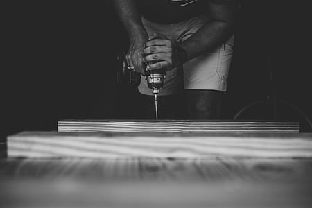 grayscaled photography of man holding power drill thumbnail