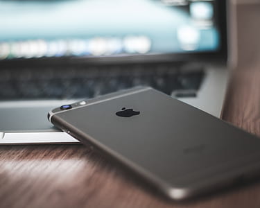 selective focus photo of space gray iPhone 6 placed on top of gray and black laptop computer thumbnail