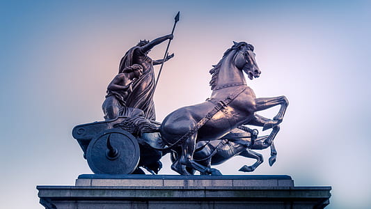 statue of man holding spear riding on chariot thumbnail