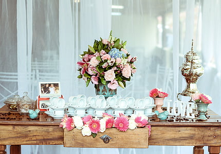 flower arrangement behind teacups and saucers on table thumbnail