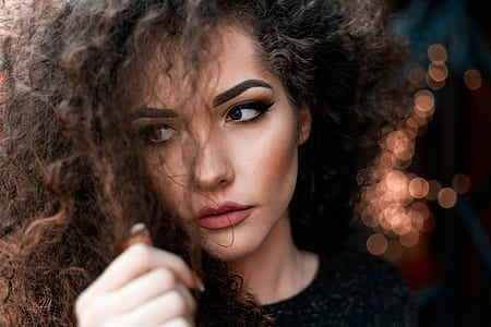 selective focus photography of woman's face holding her hair thumbnail
