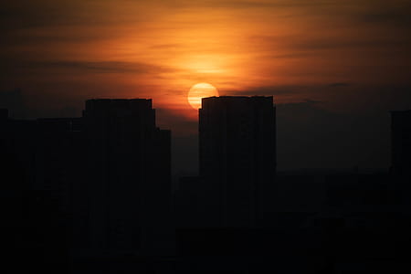 silhouette of buildings under cloudy sky photo taken during sunset thumbnail