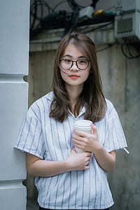 woman holding plastic cup while standing near wall thumbnail