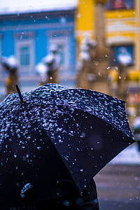 selective focus photography of person using black umbrella standing on snowed area thumbnail