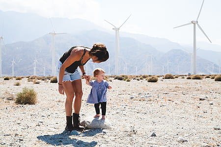 woman and child walking near wind turbines during daytime thumbnail