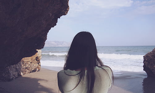 woman standing between rock near seashore thumbnail