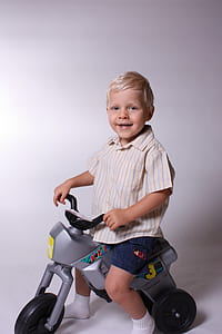 smiling boy riding trike close-up photography thumbnail