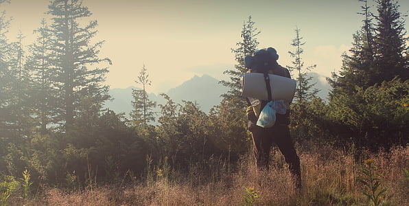 person standing on grass field surrounded by mountains thumbnail