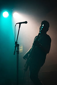 man playing bass guitar standing in front of microphone thumbnail
