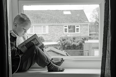 boy sitting on window reading book thumbnail