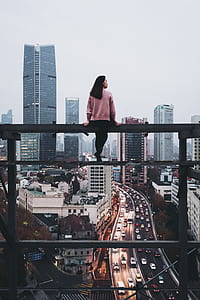 woman wearing pink sweatshirt sitting on billboard frame thumbnail