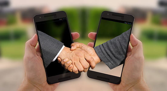 two person shaking hands and two black smartphones thumbnail