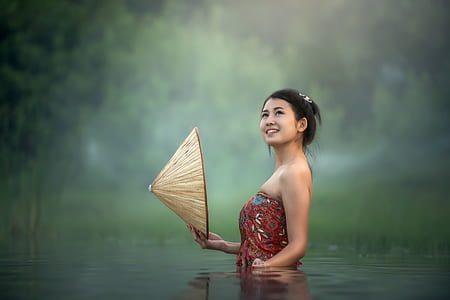 woman in water holding brown hat thumbnail