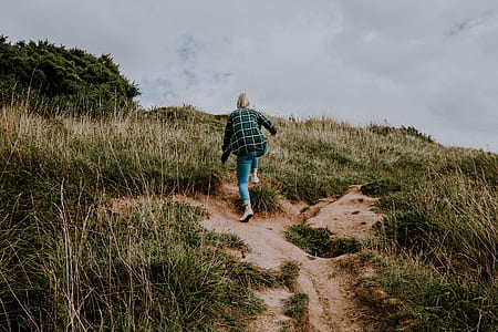 woman walking on mountain under cloudy sky thumbnail