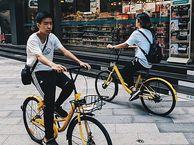 two men riding bicycles beside store thumbnail