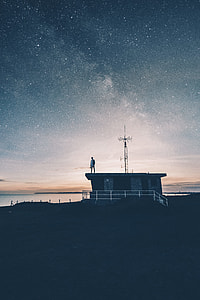 person standing on black and grey house roof during night thumbnail