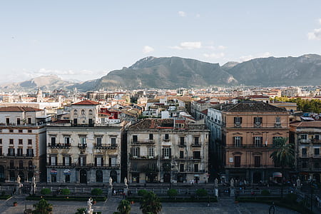 aerial view of buildings near mountain under gray sky thumbnail