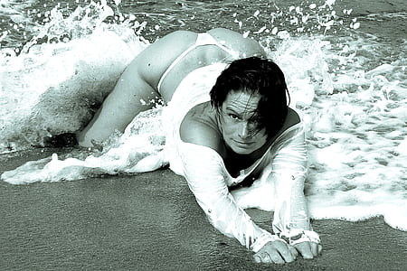 gray scale of woman lying on sea shore thumbnail