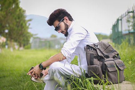 man sitting beside his backpack while looking down thumbnail