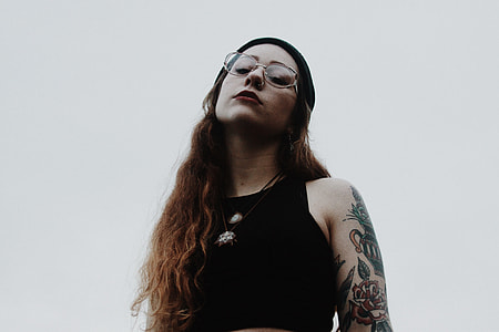 woman wearing black sleeveless top and wearing eyeglasses looking down thumbnail