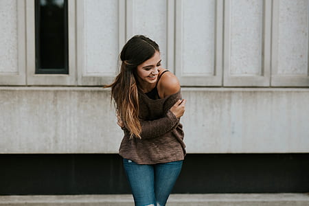 woman holding arm near white wall thumbnail