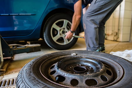 close-up photo of person changing tire of a blue vehicle thumbnail