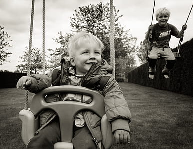 grayscale photo of two children riding swing chairs thumbnail