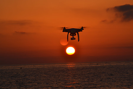 silhouette photo of flying drone over rippling body of water thumbnail
