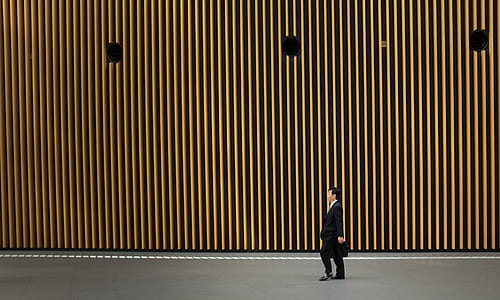 man wearing black formal suit jacket walking on gray road thumbnail