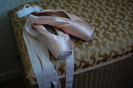pair of pink ballet shoes on brown fabric ottoman thumbnail