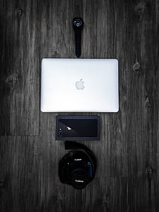 silver MacBook, black Canon camera, iPhone 8 and watch on gray wooden floor thumbnail