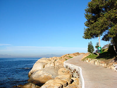brown rocks beside road and on body of water thumbnail