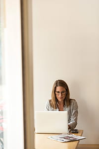 woman sitting in front of brown wooden table using white laptop photo thumbnail