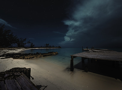 ocean near sand and dock during night time thumbnail