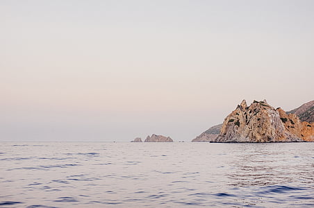 body of water beside brown rock formation thumbnail