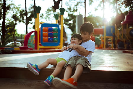 boy hugging a child sitting on ground at daytime thumbnail